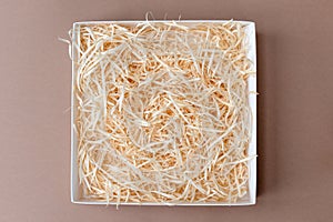 Opened gift box with decorative straw, filler, shavings.