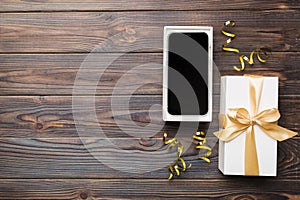Opened gift box with gold ribbon and smartphone on color background, top view. Blank open box packaging mockup