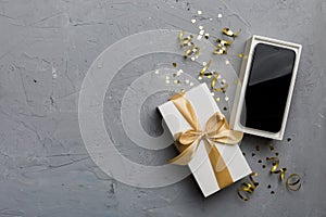 Opened gift box with gold ribbon and smartphone on color background, top view. Blank open box packaging mockup