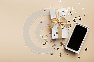 Opened gift box with gold ribbon and smartphone on color background, top view. Blank open box packaging mockup