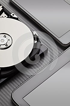 Opened hard disk drive and modern mobile devices on carbon background