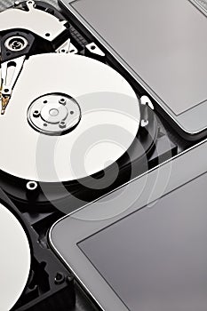 Opened hard disk drive with silver plate, modern digital tablet and mobile phone with blank screen