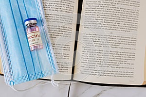 Opened the Holy Bible closeup prayer time with Negative attitude of the church to vaccination and covid-19 vaccine bottle