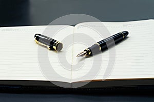 Opened lined diary notebook with a luxury pen with copy space