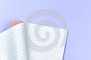 Opened lined notebook for school on a pastel purple background of office table desktop, copy space and top view photo