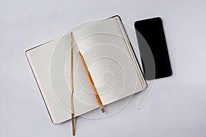 An opened note book with a bookmark, smartphone and a pencil isolated on grey background. Preparation for the business meeting