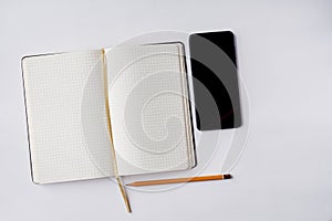 An opened note book with a bookmark, smartphone and a pencil isolated on grey background. Preparation for the business meeting