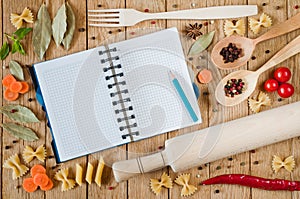 Opened notebook for recipes, vegetables and spices on a wooden table