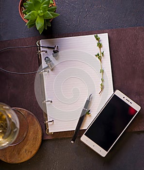 Blank open notebook, pen, earphones and phone on a wooden table