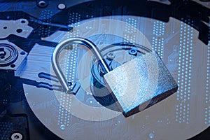 Opened padlock on computer motherboard and hard disk drive. Internet data privacy information security concept. Blue toned image