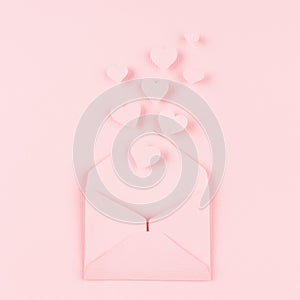 Opened paper envelope with fly out hearts as love message on soft pink color background. Valentine day concept for design.