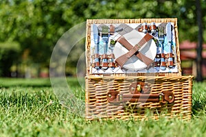 Opened Picnic Basket With Cutlery In Green Grass