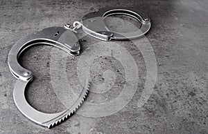 Opened police handcuffs on rough grey background with copy space.