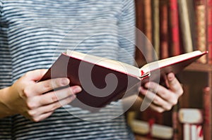 Opened red cover book in man`s hands. Soft focus