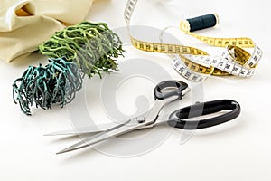 Opened scissors, tailor`s tape measure, threads and pins