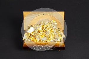 Opened single casket with golden foil as gold inside on the dark paper background, wooden box, wooden chest, treasure chest