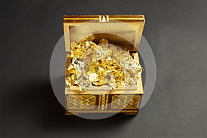 Opened single handmade casket with golden foil as gold inside on black textured paper background, wooden box, wooden chest,