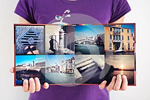 Opened square travel photo album in woman hands