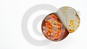 Opened tin can with fish in tomato sauce. White background. Top view. Photo.