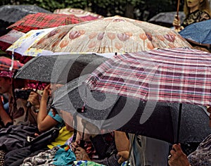 Opened umbrellas by sitting people on a rainy day