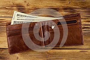 Opened wallet with american dollars on wooden table. Top view