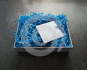 Opened White Box with Blue Crinkled Straw with Small White Envelope