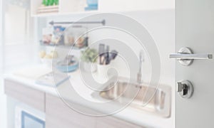 Opened white door to kitchen corner with utensil on counter