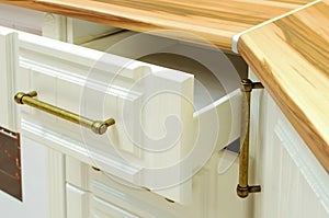 Opened white drawer in a kitchen cabinet, close-up