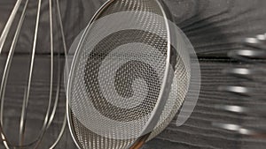 Opener, whisk, masher and strainer hanging against wooden grey wall in restaurant or home kitchen. Kitchen utensils made