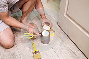 Opening a can of paint with a pair of scissors. Repair staining the doors with paint