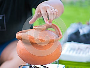Opening the cap of clay pot with hand. Cooking process on tourist camp.