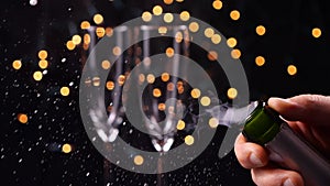 Opening champagne bottle closeup. Sparkling Wine over Holiday Bokeh Background. Slow motion