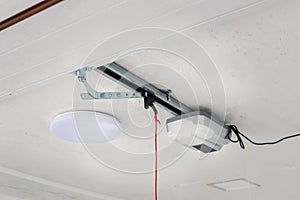 Opening door and automatic garage door opener electric engine gear mounted on ceiling with emergency cord. Double place empty