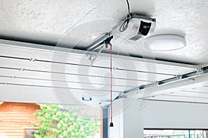 Opening door and automatic garage door opener electric engine gear mounted on ceiling with emergency cord. Double place empty