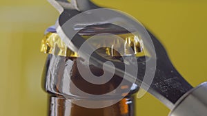 Opening drink dark bottle with bottle opener on yellow background