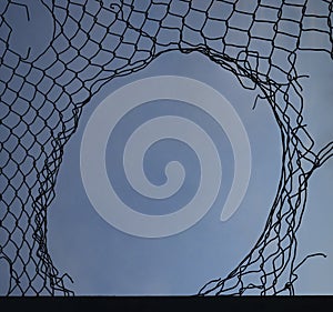 Opening in metallic net fence. isolated on blue sky background. Challenge. uncertainty. breakthrough concept. freedom concept.