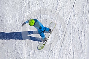 Opening of a ski resort, a young man on a snowboard on a background of mountains. Aerial view