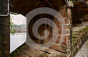 Opening in stone arch bridge over river in cloudy autumn morning