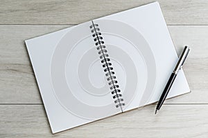 Opening white blank note paper and pen on light grey wooden table background with copy space