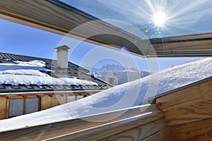 Opening window on a roof covering with snow in an alpine cottage