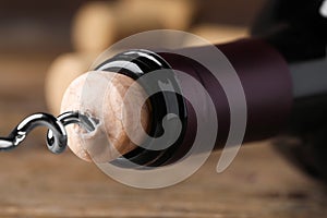 Opening wine bottle with corkscrew on background, closeup