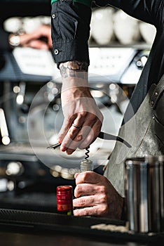 Opening a wine bottle with corkscrew in a bar