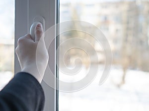 Opens the window with his hand to ventilate the room. White window opens for fresh air opens the window photo