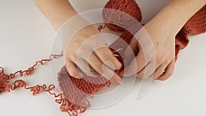 Opens the yarn and twists it into a ball.Female hands close-up on a white table.