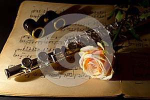 Opera glasses, silver flute and yellow rose on an ancient music score