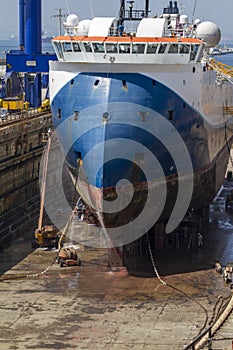 Workers cleaning the hull of a merchant ship in the dry dock photo