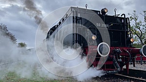 Operating German steam locomotive on railway. Retro steam train with smoke