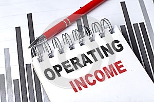 OPERATING INCOME text written on notebook with pen on chart