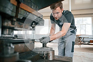 Operating manufacturing equipment. Man in uniform is in workstation developing details of agriculture technique