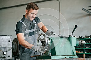 Operating manufacturing equipment. Man in uniform is in workstation developing details of agriculture technique